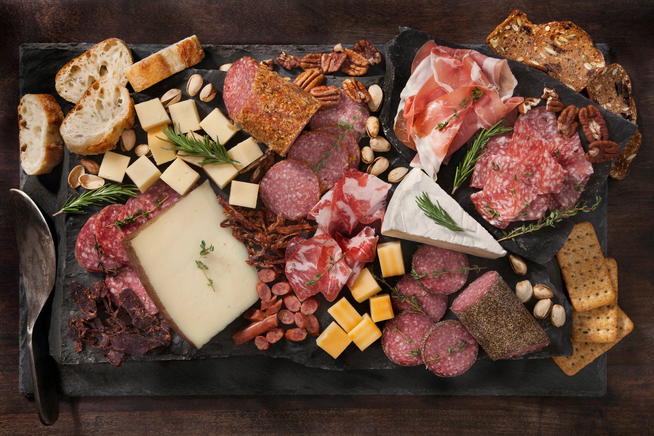 Beautifully arranged charcuterie board with bread, nuts, and cheeses
