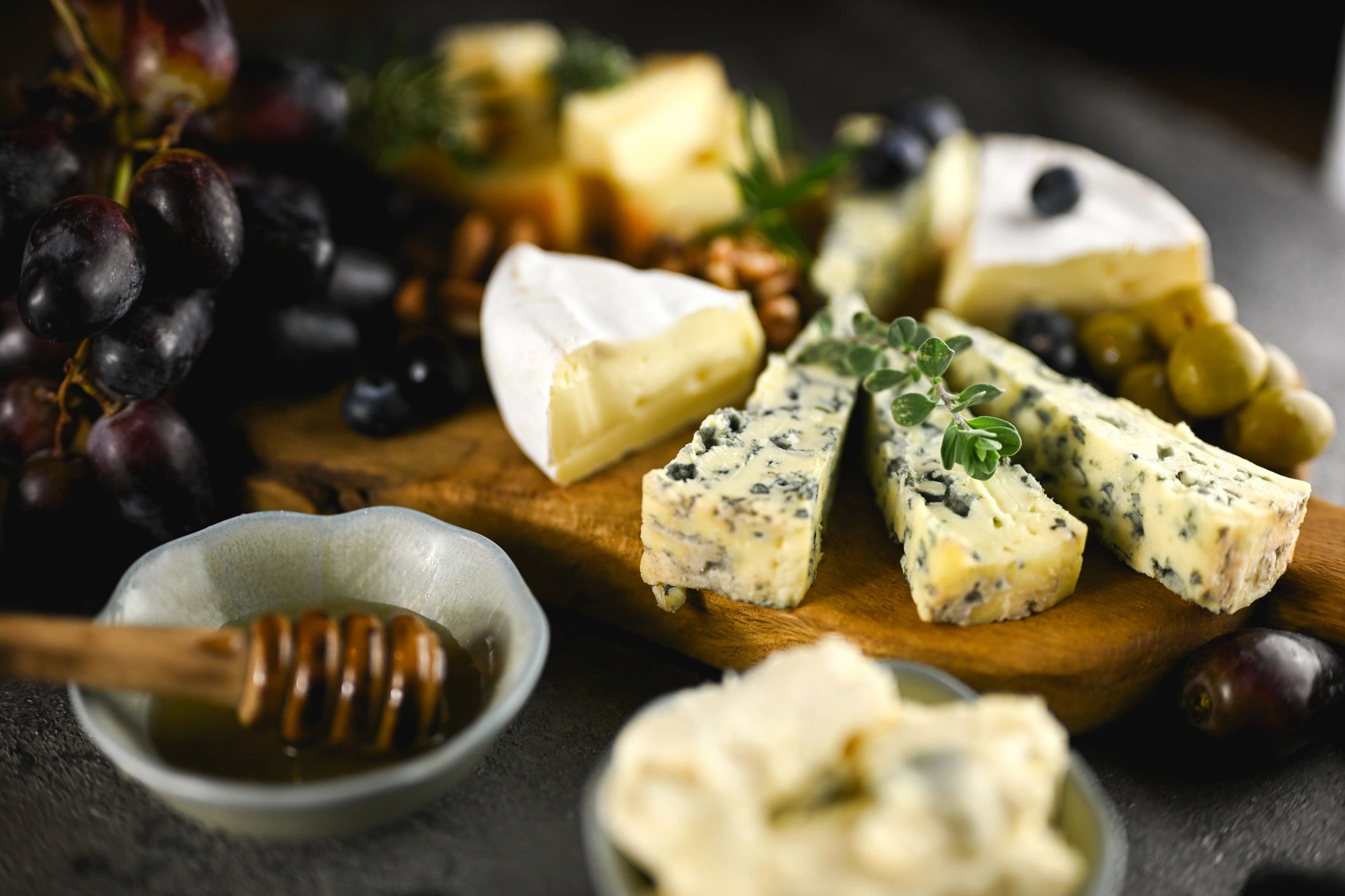 Gourmet cheese board with cheeses, olives, grapes, and honey
